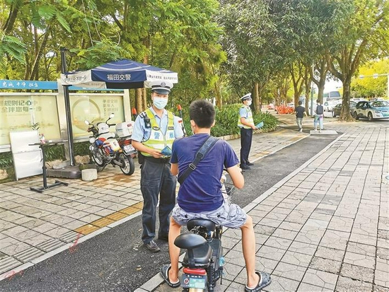 昨日，交警在街头劝导骑电单车者戴头盔。