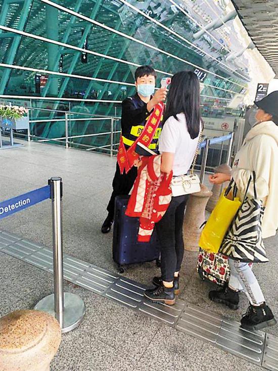 深圳机场工作人员对进入航站楼的旅客进行体温检测。
