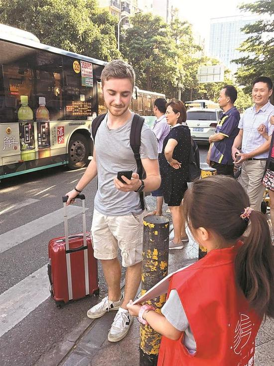 ▲南山区小志愿者街头推广爱心待餐,获外国友人支持。