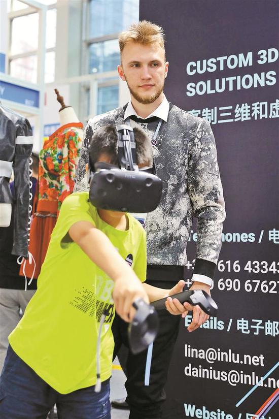 ▲丹尼尔斯·斯达拉指导小男孩体验立陶宛VR技术。