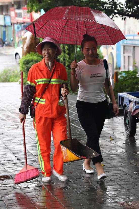 华龙路上，市民为环卫工撑伞。
