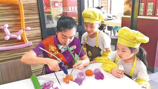 ▲龙华区民治小志愿者在真功夫店员的指导下,有模有样地做出了爱心花朵。