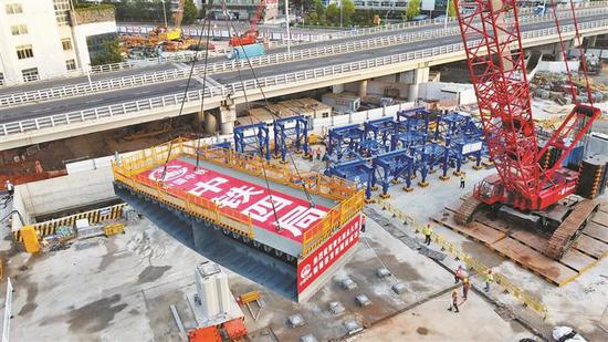 6月16日,随着现场起重指挥一声令下,400吨履带吊机启动,一段钢箱梁缓缓升起,黄木岗枢纽永久桥进入钢箱梁安装阶段。 深圳商报记者 廖万育 通讯员 罗思明 摄