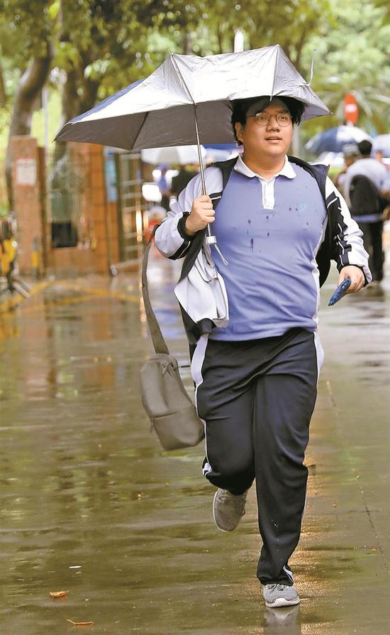 举着被风吹翻的雨伞，考生充满自信地跑进福田区外国语高级中学考点。