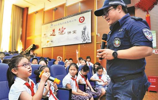 ▲民警在“安全教育进校园”活动中与小学生进行互动。