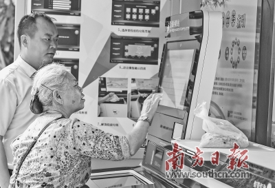 在深圳市盐田区上东湾小区,一名老人在物业管理人员的指导下给厨余垃圾称重。居民通过垃圾分类称重可以获得积分,并获得不同的小奖励。 新华社发
