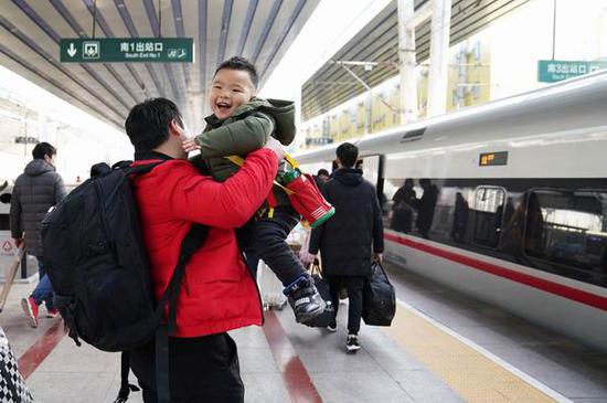 2018年2月1日,在北京西站,一位旅客抱起小朋友准备乘坐G557次列车。新华社 图