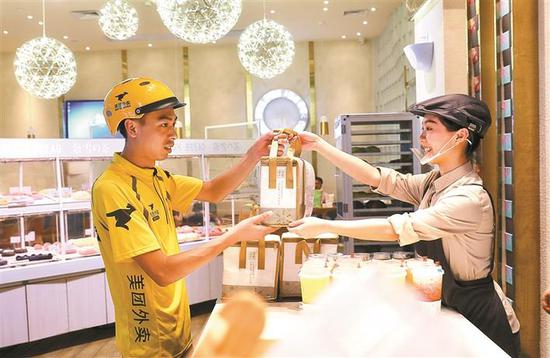 美团外卖小哥接过饮品 深圳商报记者 钟华登 摄