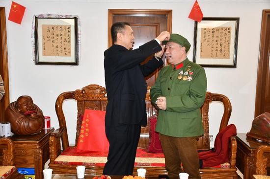 看到老兵陈武贤的军帽帽徽有点歪，张悦华局长细心帮他整理。