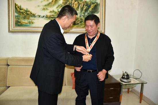 张悦华局长为老兵韦学锋佩戴建国七十周年纪念奖章。