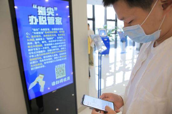 在深圳市龙华区税务局智能办税大厅,纳税人正在使用智税通微信小程序查看取号情况