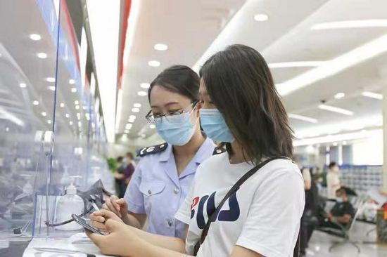 深圳市龙岗区税务干部带领纳税体验官在办税服务厅窗口体验新办纳税人套餐,并为其详细讲解电子税务局相关业务功能。