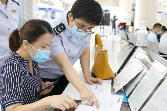 深圳市龙岗区税务干部带领纳税体验官在办税服务厅窗口体验新办纳税人套餐,并为其详细讲解电子税务局相关业务功能。
