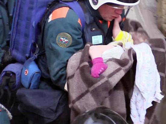 男婴获救后，一名救援人员抱起他，裹上毯子，跑向救护车。