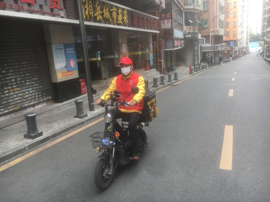美团外卖小哥在街上进行防疫知识宣传