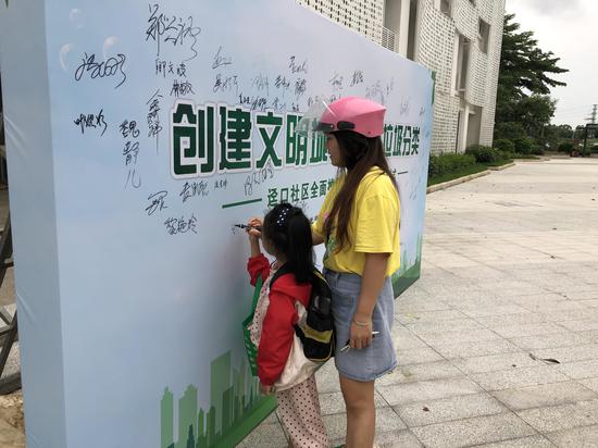 社区居民在自愿参与垃圾分类背景墙上签名