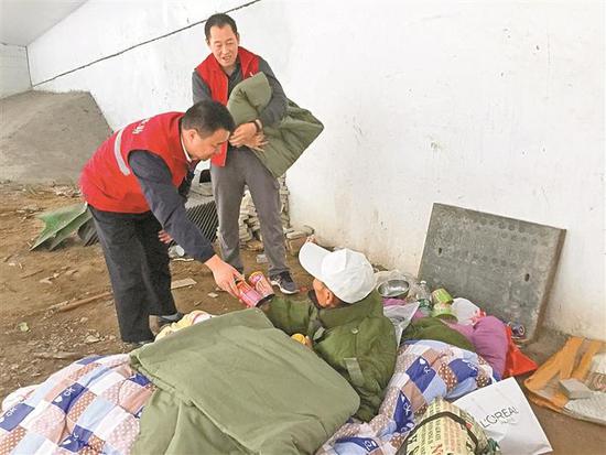 救助站工作人员给露宿街头者送上御寒物品和食物。 深圳晚报记者徐斌 摄