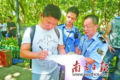 在深圳罗湖区东湖公园,吸烟男子在罚单上签字。