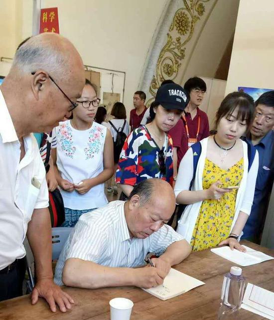 沈鸿根先生在为书法爱好者签名留念