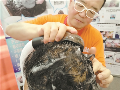 工作人员正在用洗发机为体验者洗头。