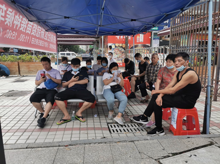 铁岗社区居民在铁岗社区大门口候车点等待专车的接送
