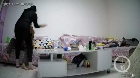 ▲老人跌坐在沙发后,女子朝着老人头部进行殴打。来源/视频截图