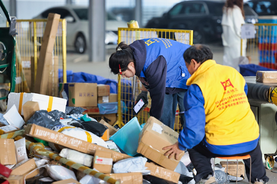 ▲陕西扶风县拼多多快递进村中转仓内，工作人员正在按照村点归集包裹。张宸豪|摄