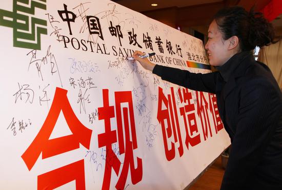 邮储银行员工在“合规 创造价值”宣传板上签名