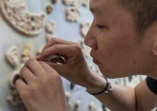 李博正在用麻绳按图拼制