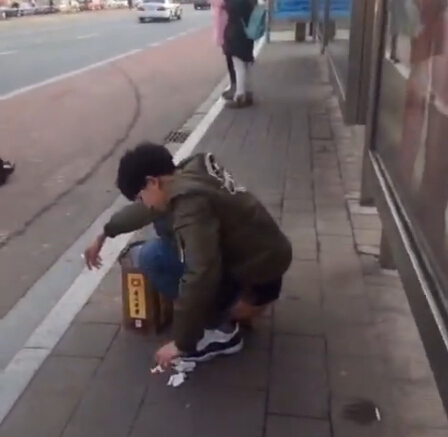 男孩公交站台前边抽烟边拉屎,若无旁人 纹丝不动