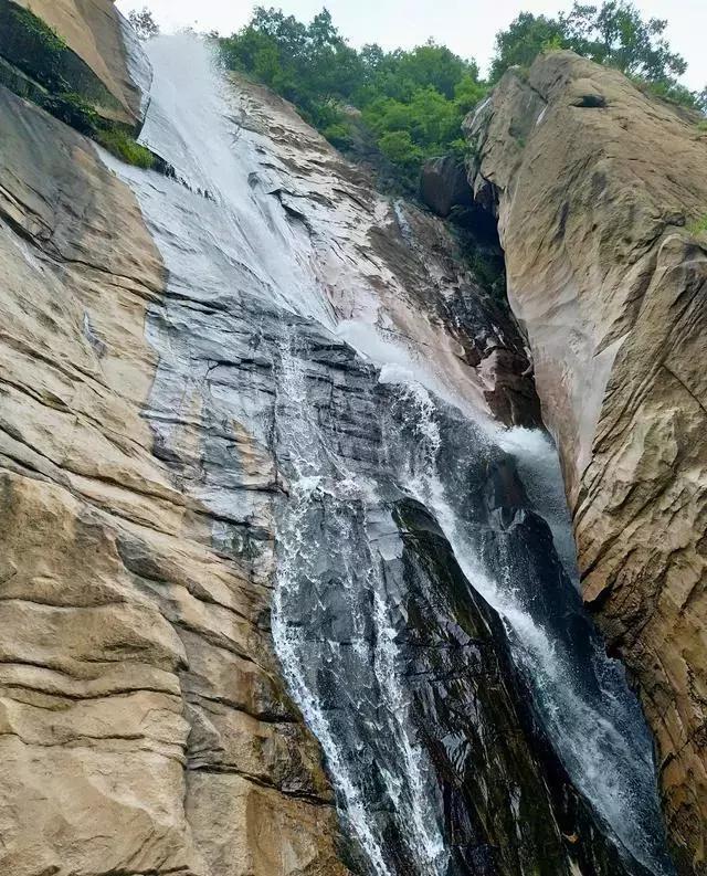 潺潺,谷底深处百米高的瀑布立壁悬空,似白练般飘然溅落,如琼浆漫溢,湿