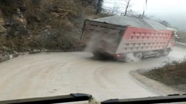 重型卡车，下坡加急转弯这么危险，装得太满了，石子一路散落