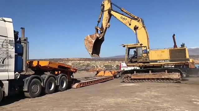 曼重型运输卡车并排承载卡特挖掘机，整个大家伙出动