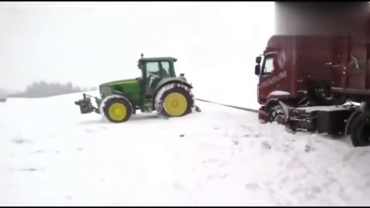 冷天雪地里拉拽着运输卡车的拖拉机