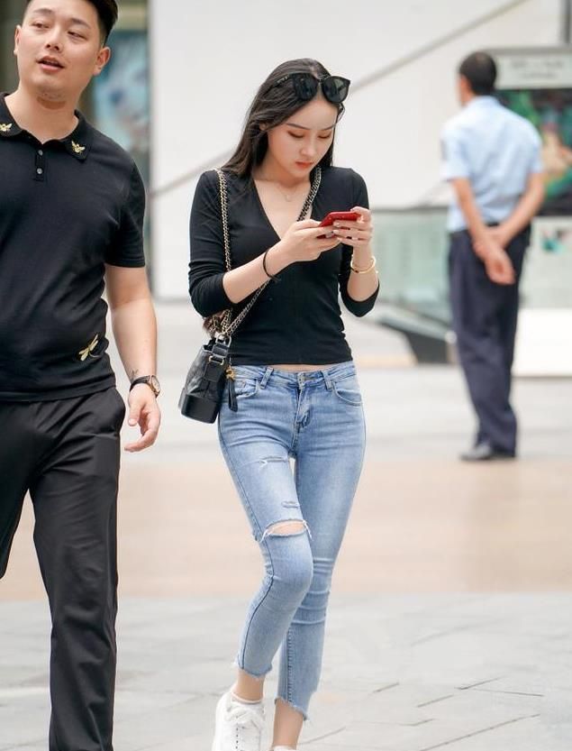 小姐姐有一个好身材,黑色的上衣,下面配上一条牛仔裤,再搭双小白鞋