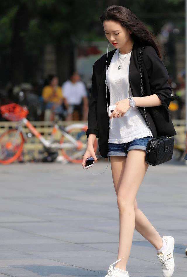 街拍:女孩白色上衣搭配牛仔短裤,低头走路的样子成为街上的焦点
