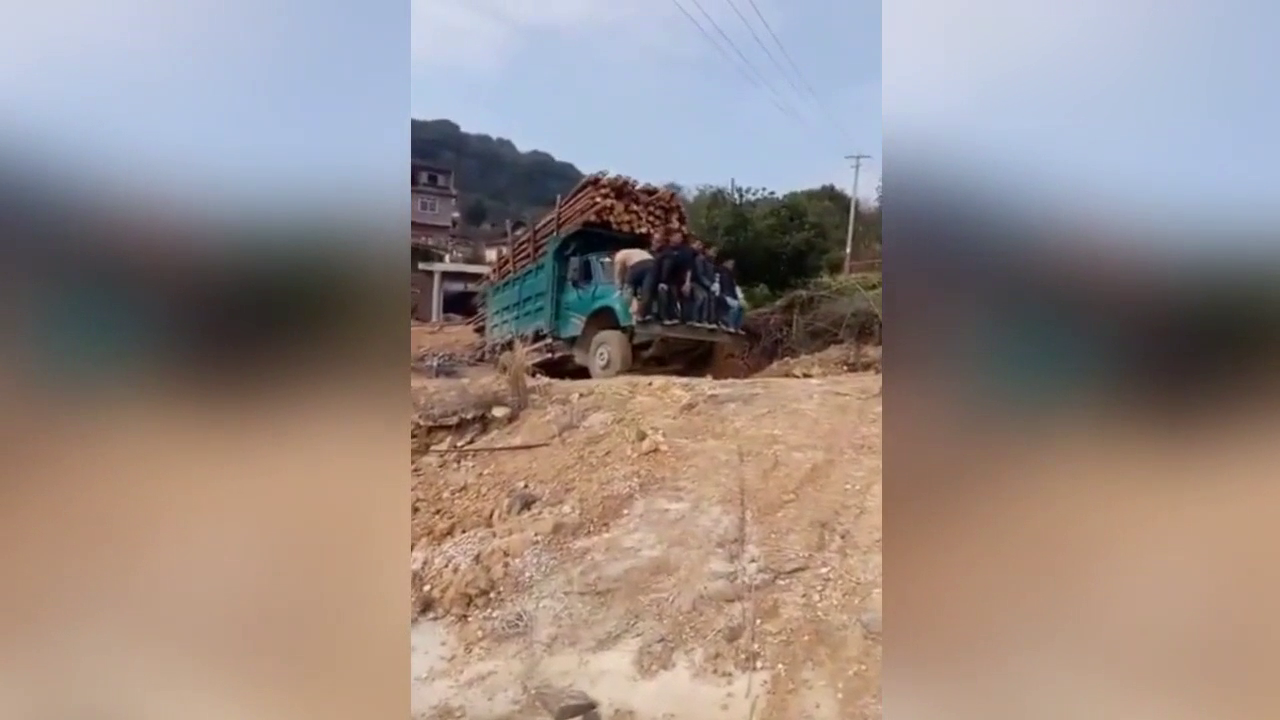 实拍载满木材的卡车瞬间侧翻 木头滚落一地