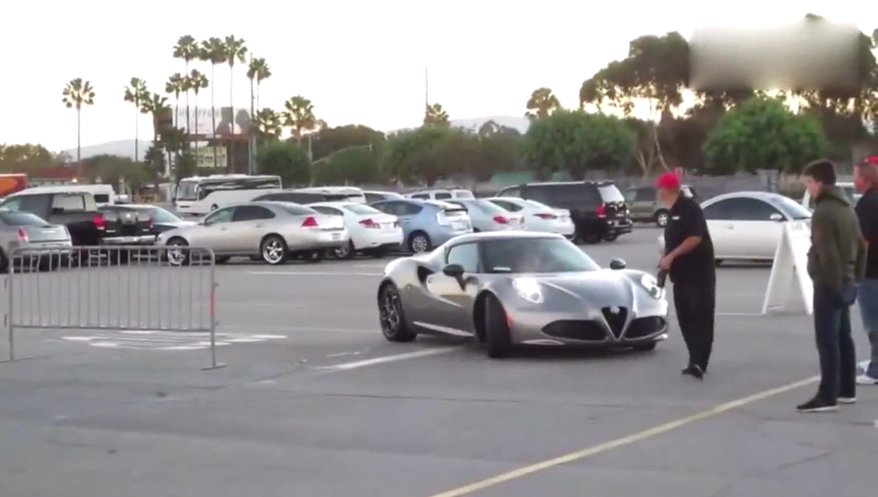 一辆阿尔法罗密欧跑车停在广场，旁边拍照的小伙亮了