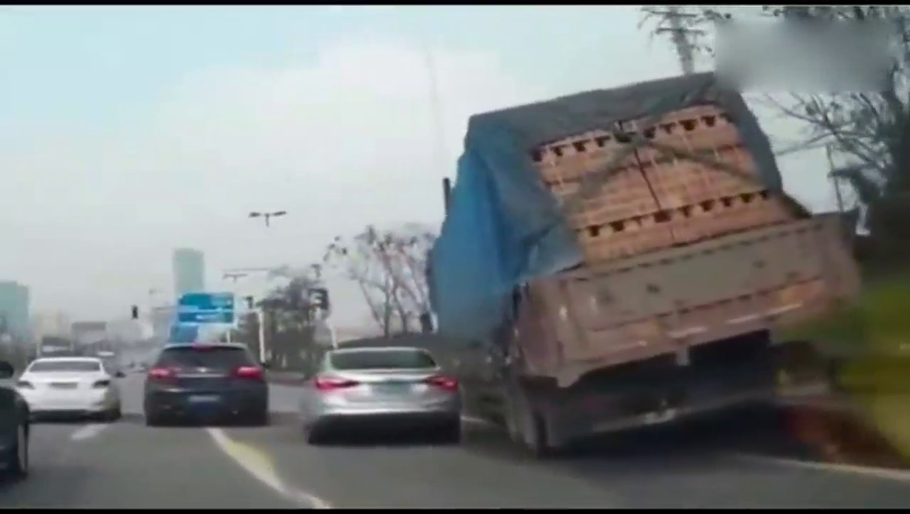 拉砖卡车驶上马路牙子，全车侧翻砖块活埋小轿车