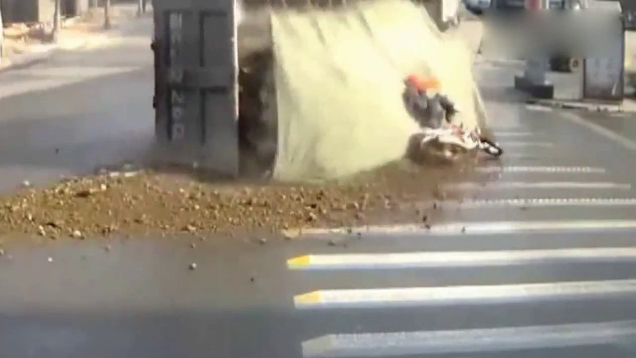 装满砂石的卡车突然失控侧翻 摩托骑士经历生死一刻