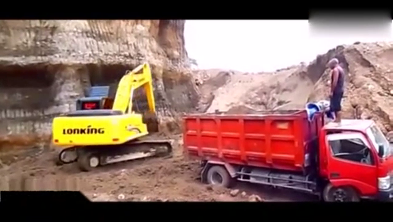 新司机开挖掘机装载泥土，一旁还要卡车师傅指挥着