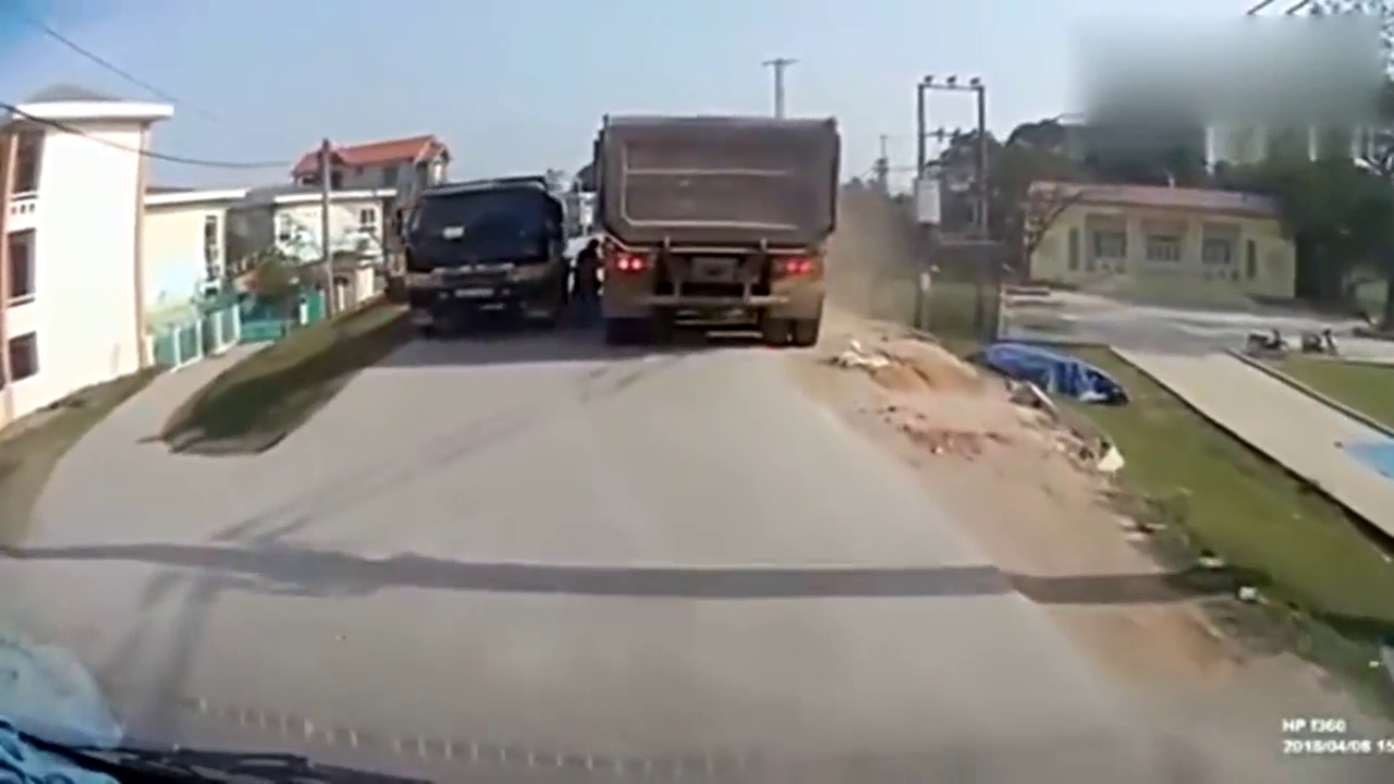 两个孩子在卡车之间穿行，还好司机及时刹车，不然就悲剧了