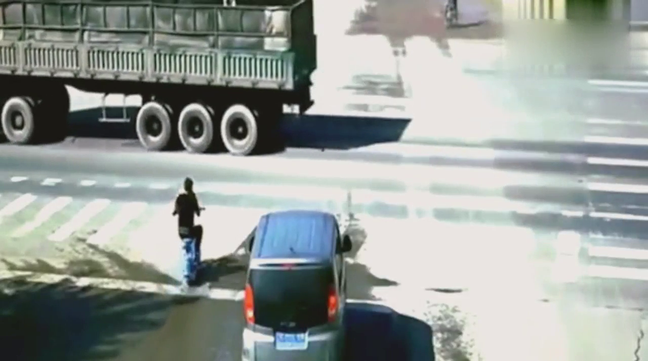 电动车小伙打着手机闯红灯，惨遭碾压，害人害己