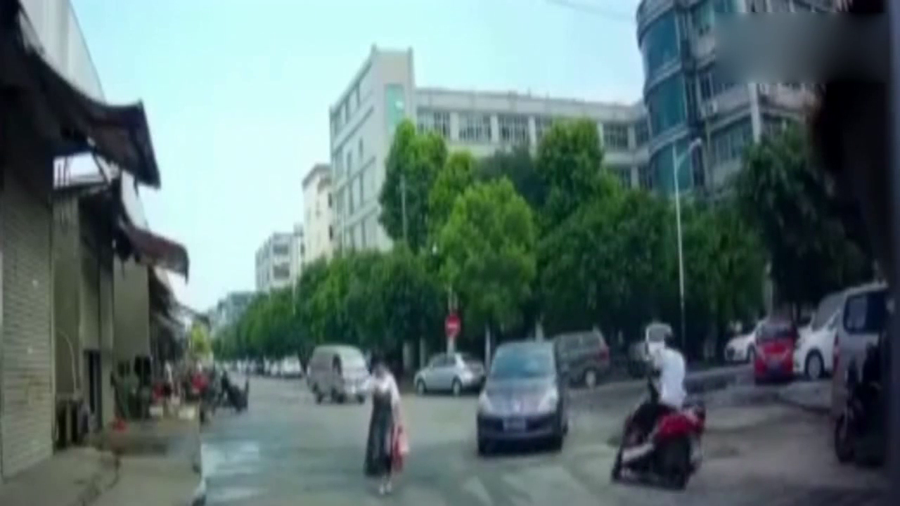 妹子在马路上看手机，轿车跟在后面不敢加速，电动车却突然出现了