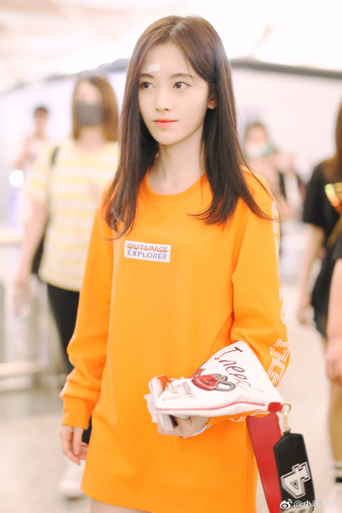 鞠婧祎穿橙色卫衣现身机场皮肤白皙,额头上贴