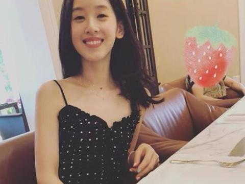 奶茶妹妹一袭黑色吊带裙微笑坐餐桌前，一旁是女儿是谁照的相呢？