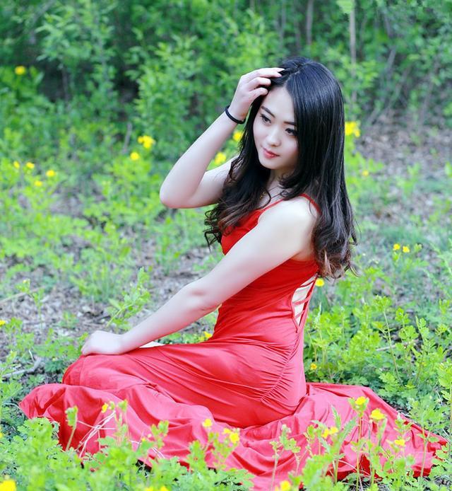 户外美景下一个长发飘逸的美丽红裙姑娘