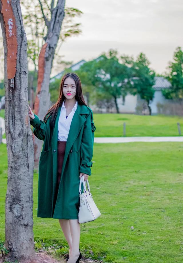 绿色大衣里面搭上一件白衬衫,配上吊带高腰裙,手上提的包包是米白色
