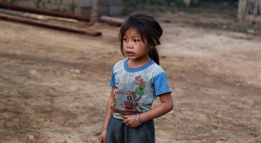老挝农村的生活条件不好,小女孩穿的衣服有些脏乱,但是看上去特别天真