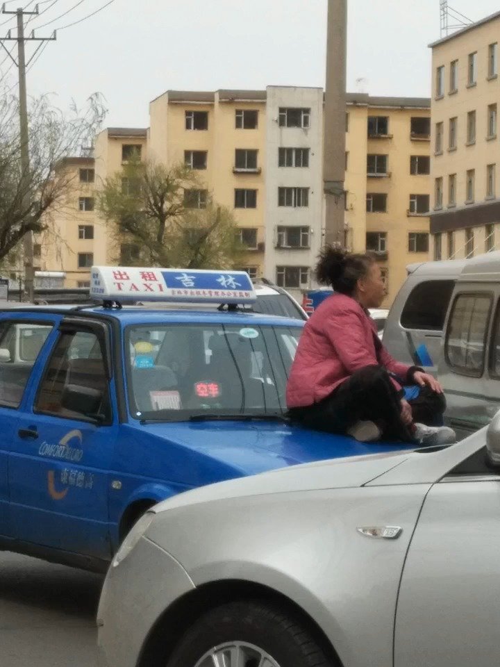 昨日中午吉林市内一中年女子坐在一辆出租车的机顶盖上原因不明